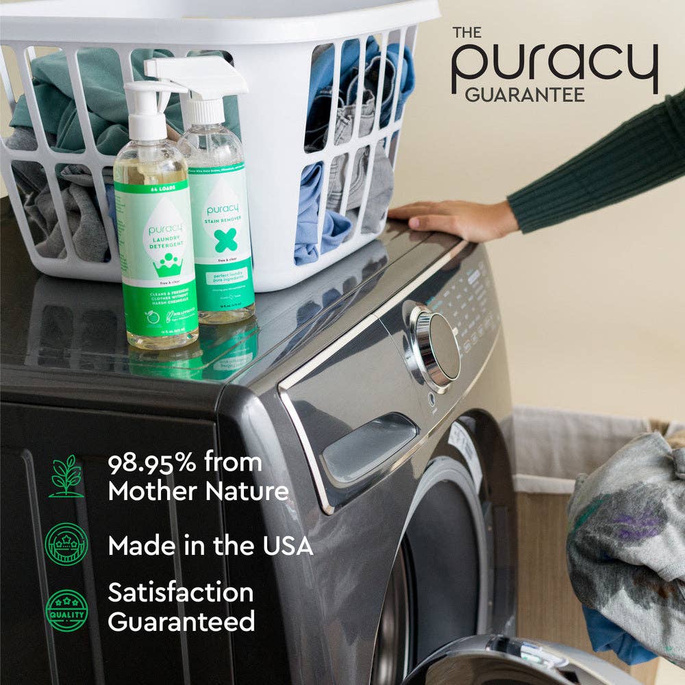 A person leans on a washing machine with a basket of clothes on top. Nearby are two Puracy Natural 10x Laundry Detergent bottles, ideal for sensitive skin. Text reads: 98.95% from Mother Nature, Made in the USA, 1,4 Dioxane Free, Satisfaction Guaranteed.