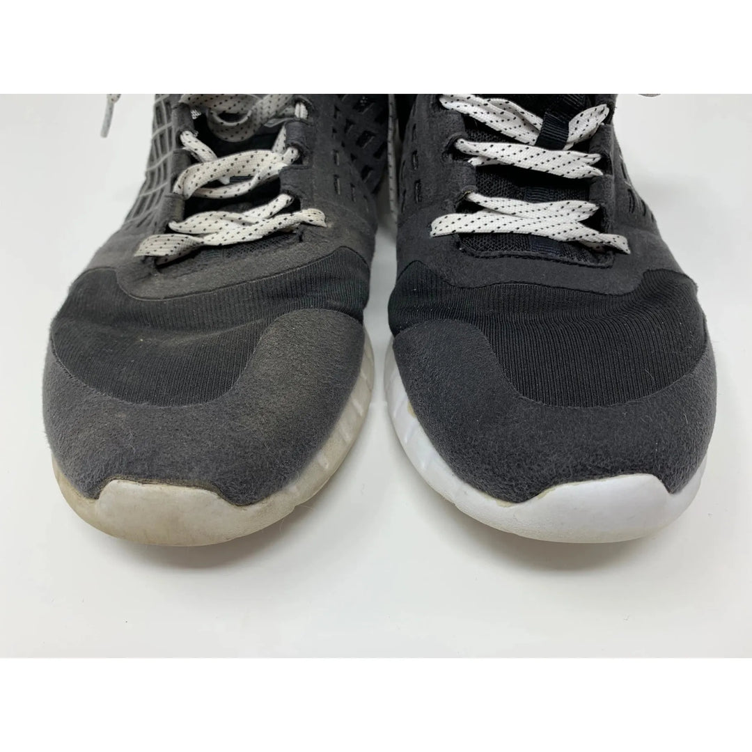 A pair of worn black and white sneakers with white laces shows noticeable discoloration on the right shoes toe. The SneakERASERS Shoe Eraser SOAK, Sneaker Detergent (5 packs), could refresh them, making the shoes look like new against their pristine white background.