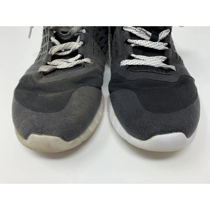 A pair of worn black and white sneakers with white laces shows noticeable discoloration on the right shoes toe. The SneakERASERS Shoe Eraser SOAK, Sneaker Detergent (5 packs), could refresh them, making the shoes look like new against their pristine white background.