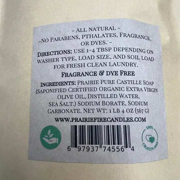 The label of Prairie Fire Candles Prairie Pure Castile Organic Olive Oil Laundry Powder (Fragrance-Free, 1lb 4oz) highlights its all-natural formula ideal for sensitive skin. Free from parabens, phthalates, fragrance, and dyes, it includes usage directions, ingredients, website details, and certification icons.