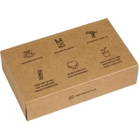 The BAMBOO Clothespins/Pegs - Pack of 20 by Zero Waste Club comes in a brown cardboard box adorned with illustrations showcasing usage, like hanging clothes and sealing packets. The packaging emphasizes its ethical production and plastic-free promise, with a tree planted for each sustainably sourced bamboo purchase.