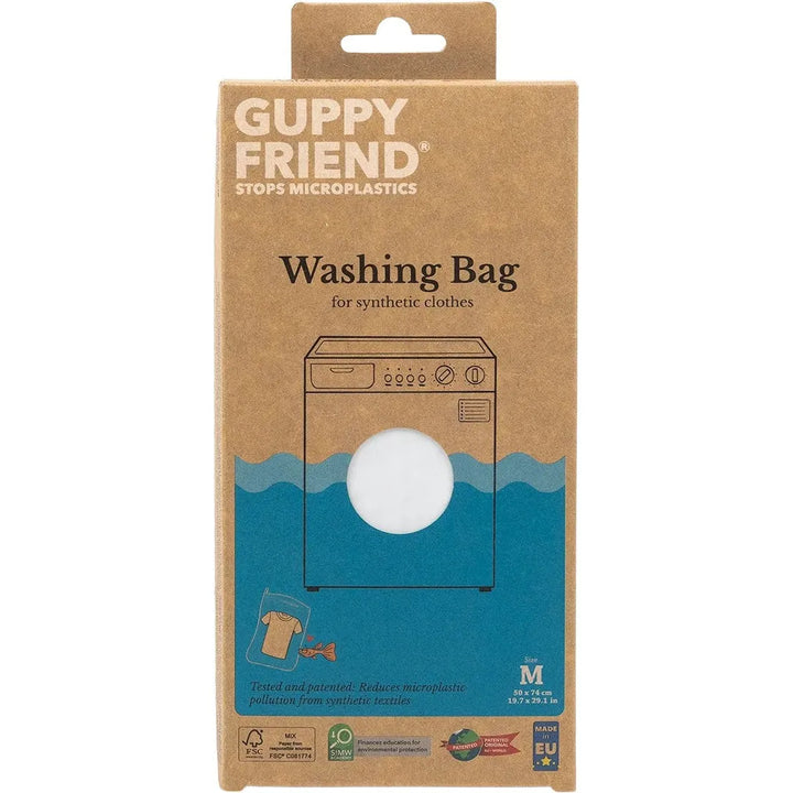 The image features the GUPPYFRIEND Washing Bag-Medium (19.7 in. x 29.1 in.) packaging, which highlights its role in reducing fiber shedding from synthetic clothes. The box showcases a washing machine illustration, emphasizing thorough testing and sustainability credentials.
.