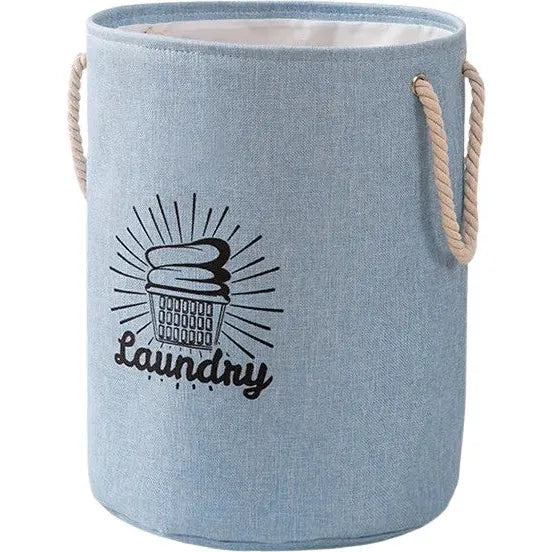 The All Things Laundry Cotton and Linen Collapsible Clothes Laundry Hamper features a blue fabric exterior, rope handles, and a printed design of an overflowing laundry basket with Laundry elegantly displayed beneath it, combining style and functionality. Available in two colors.