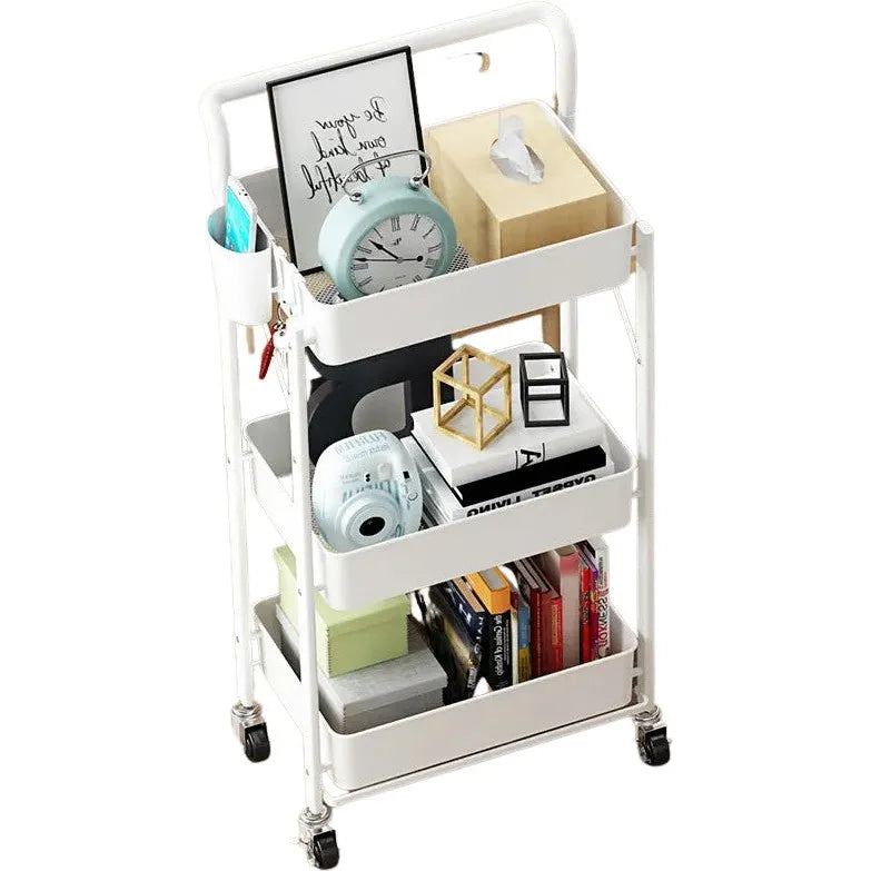 The 3 Tier Folding Laundry Room Storage Cart by All Things Laundry holds various items like a blue clock, decor, tissue box, books, a small camera, and writing supplies. Equipped with handle and roller wheels for easy mobility.