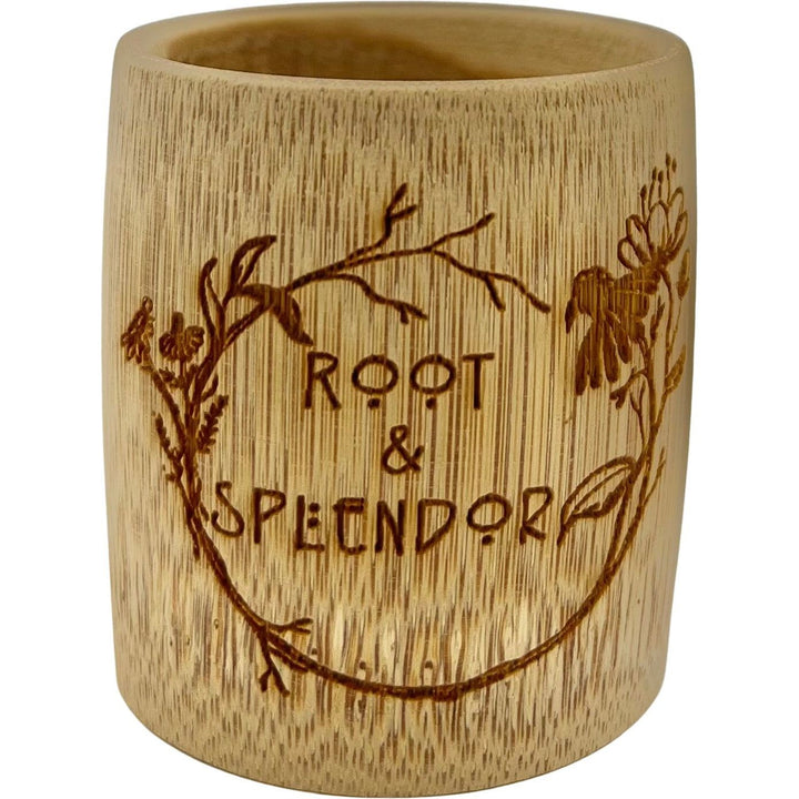 The BAMBOO Measuring Cup by Root and Splendor is a sustainable bamboo cup featuring the Root and Splendor engraving, surrounded by an intricate floral design with visible wood grain and delicately carved branches and flowers.