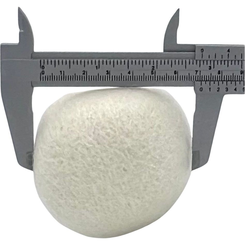 A white stone is measured with a gray caliper, showing a width of about 2.8 cm, similar to the size of All Things Laundrys 7cm large wool dryer balls used as reusable fabric softeners to reduce static cling.