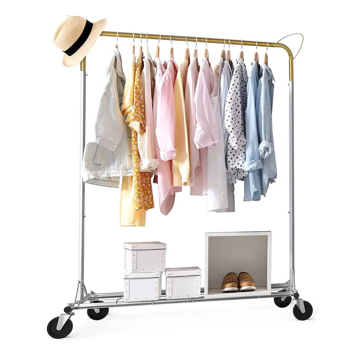 An Above Edge Hanging Garment Rack with Shelf is filled with pastel shirts and patterns, topped by a straw hat. Below, there are three white storage boxes and a pair of shoes. This clothes rail comes with wheels for easy mobility.